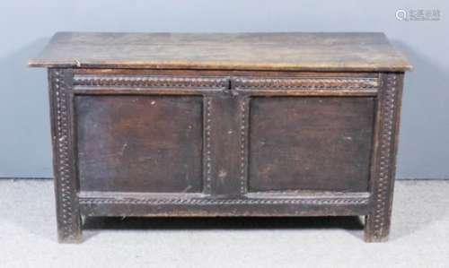 A 17th Century panelled oak coffer with plain two plank top, twin panels to front with carved rails,