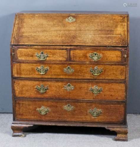 A George III oak bureau, the slope enclosing pigeon holes, central cupboard and nine small