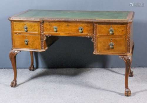 A 1930's figured walnut kneehole desk with carved edge to top and inset with green leather, fitted