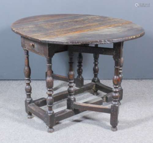 An 18th Century oak oval gateleg table, fitted one frieze drawer, on baluster turned legs and turned