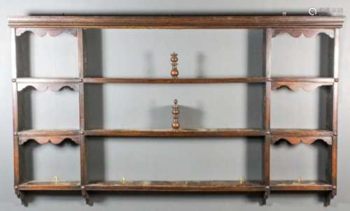 An 18th Century elm Delft rack with moulded cornice, fitted nine shelves, the smaller with shaped
