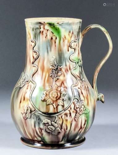 An 18th Century creamware pottery tankard with Whieldon type glaze moulded with flowers, 7.25ins