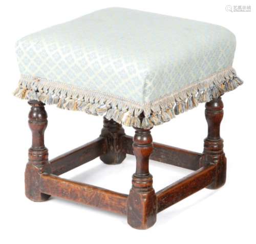 A Charles II upholstered oak stool, the seat with a later fabric cover, on turned legs united by