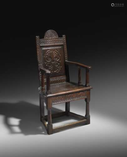 A rare James I oak caqueteuse armchair attributed to Salisbury, with a foliate lunette crest above a