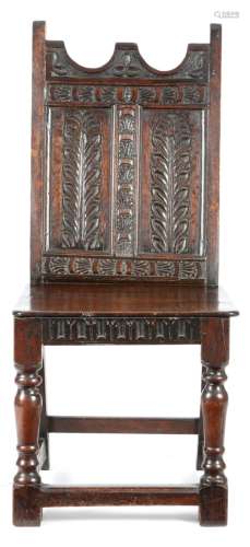 An oak side chair, the panelled back carved with leaves, above a solid seat and an arcaded thumbnail
