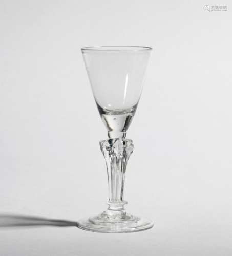 A wine glass c.1750-60, the rounded funnel bowl raised on a six-sided pedestal stem with basal