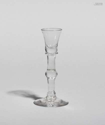 A rare cordial glass, c.1715, the small rounded funnel bowl raised on a heavy plain stem with
