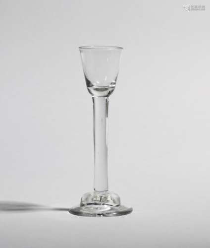An Irish cordial glass c.1740, the small rounded funnel bowl raised on a thick plain stem above a