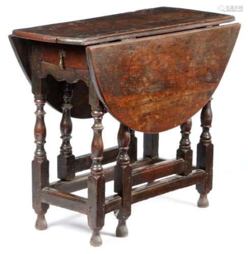 A small Queen Anne oak gateleg table, the oval drop-leaf table above a frieze drawer and on ring