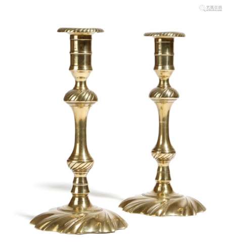 A pair of George III brass candlesticks, each with an urn shape nozzle above a knopped stem and a