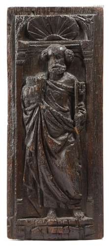 A 17th century carved oak panel, depicting Saint Peter, holding a key and a book, in an arched niche