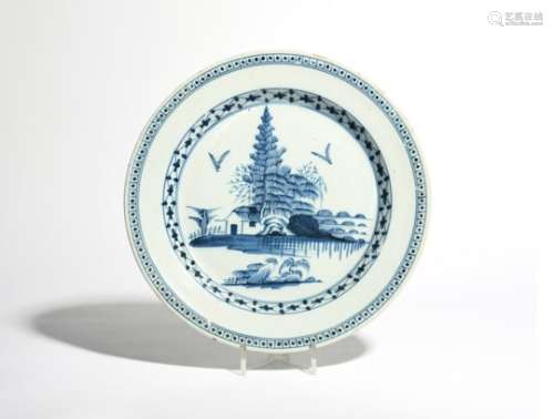 A delftware charger c.1750, painted in blue with tall pine trees above a low hut, the cavetto with a