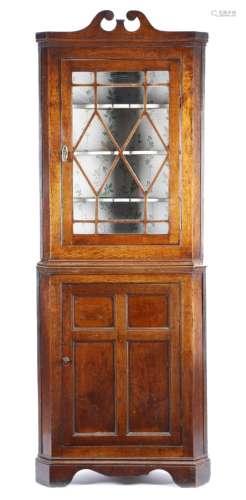 A late George III oak standing corner cupboard, with reeded mouldings, the swan neck cornice above
