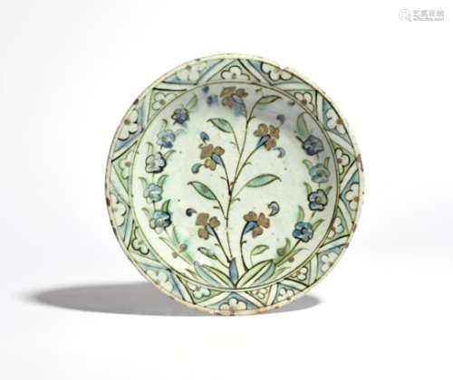 An Iznik pottery dish 17th century, painted in blue, green, red and black with tall flowering