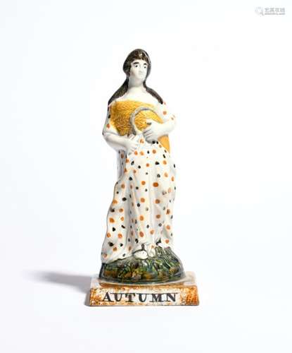 A Pratt ware figure of Autumn c.1815, modelled as Ceres holding a sheaf of corn and a sickle,