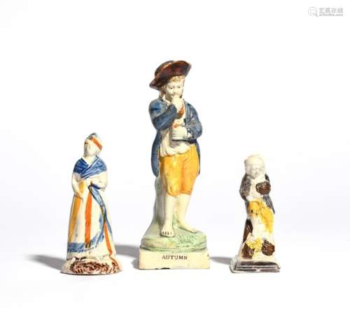 Three Pratt ware figures c.1800, one of Autumn, modelled as a young boy eating grapes, raised on a