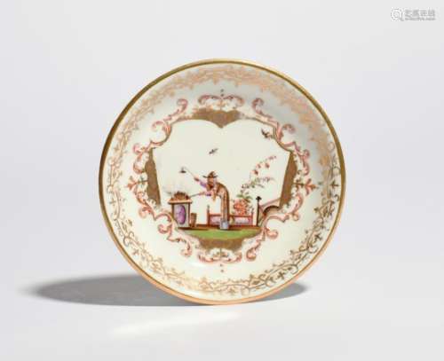 A Meissen saucer c.1725, painted with a Chinaman bending over hot coals with a pair of tongs, with