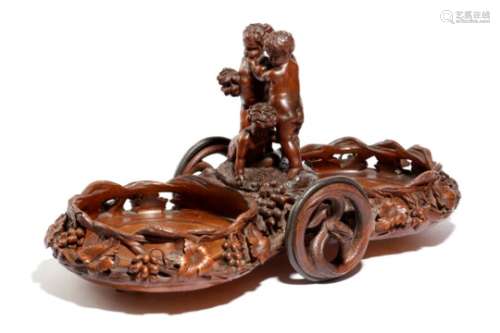 A late 19th century Black Forest carved wood table wine coaster, the centre with three frolicking