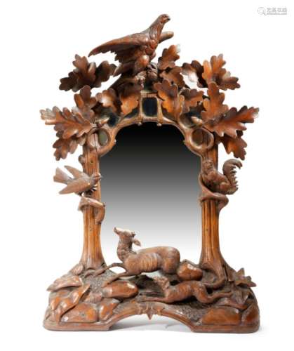 A late 19th century Black Forest wall mirror, the shaped plate within a naturalistic frame carved
