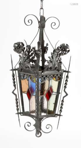 A wrought iron hall lantern, decorated with scrolling leaves and flowers, with four leaded stained