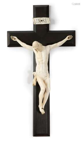 λ A continental carved ivory Corpus Christi, mounted on an ebony cross with a banner 'INRI',