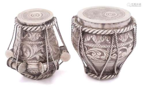 Two Indian white metal pots in the form of drums: having rope tied foliate and scroll decoration,