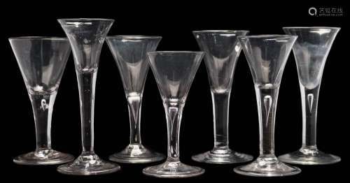 Seven wine glasses: each trumpet shaped bowl tapering into a straight stem,