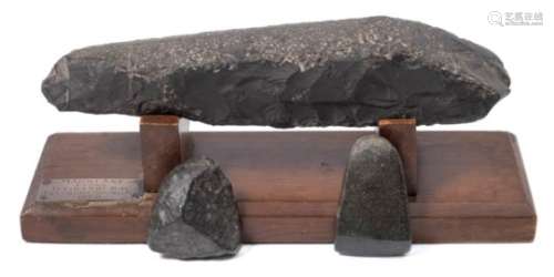 A Maori stone axe head: mounted on a wood stand, bears label 'Maori Axe found Titirangi Bay,