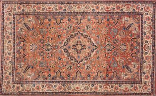 A pair of Kashan rugs:, the brick red fields each with an indigo cartouche pole medallion,