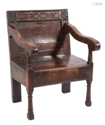 A 17th century oak open armchair: the panel back with strapwork decorated top rail flanked by