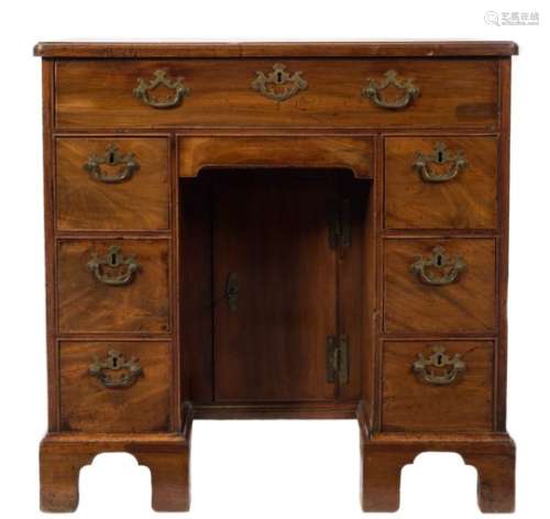 A George III mahogany kneehole desk:, the top with a moulded edge and rounded corners,
