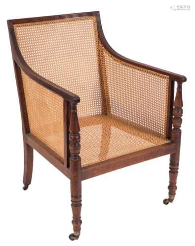 A Regency mahogany bergere armchair,: with a reeded frame, having curved cane panel back,