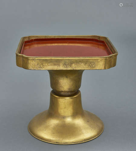 A Japanese square brass stand on a round diabolo shaped base