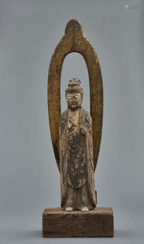 A large Japanese wooden standing Buddha with a mandorla