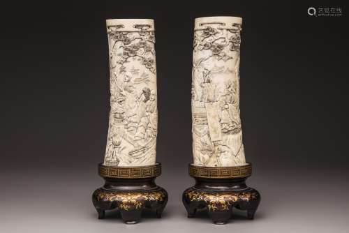 A pair of Japanese carved tusks on a wooden base