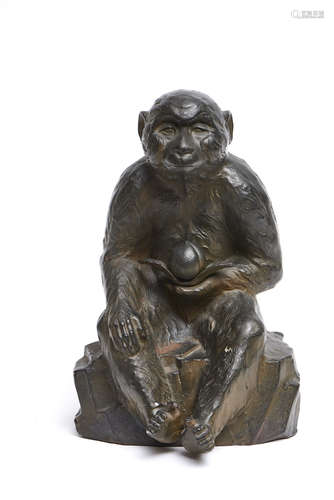 A large Japanese bronze figure of a monkey sitting on a rock with a peach in its hand