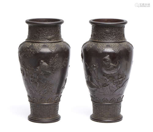 A set of two Japanese bronze vases both decorated with a relief of birds, lotus flowers and trees.