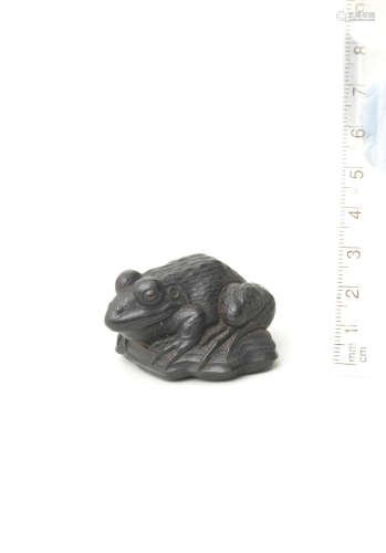 Attributed to Seiyodo Tomiharu (1733-1810), Iwami Province, late 18th/early 19th century An ebony netsuke of a frog on driftwood