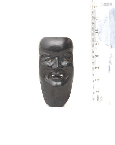 By Seiyodo Tomiharu (1733-1810), late 18th/early 19th century A kurogaki (black persimmon) wood mask netsuke