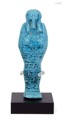 An Egyptian white-glazed composition shabti, 19th-20th Dynasty, modelled with crossed arms and