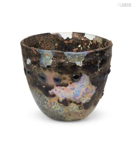 A heavily-weathered late Roman glass beaker, 4th century A.D., decorated with a horizontal row of 17