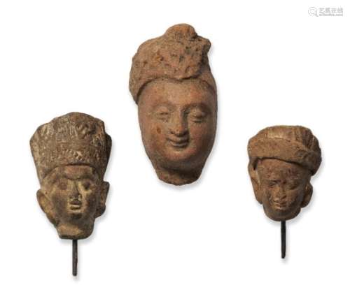 Three small red stone heads, India, 10th-12th century, one with finely moulded features, two with