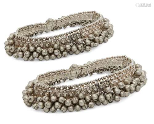 A pair of silver anklets, India, 20th century, composed of a series of panels fringed with bell