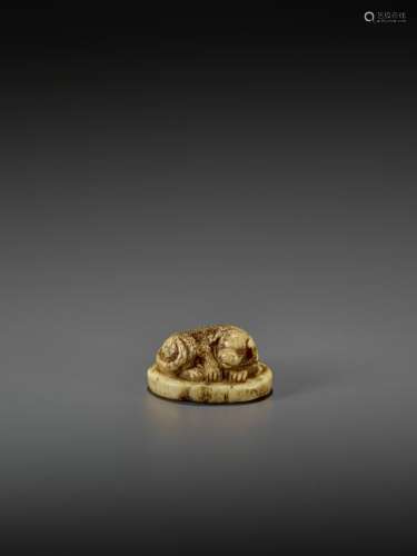 A STAG ANTLER NETSUKE OF A DOG ON A CUSHION