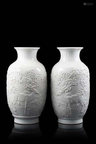 A pair of white porcelain cylindrical vases, each decorated in relief with deer amongst pine