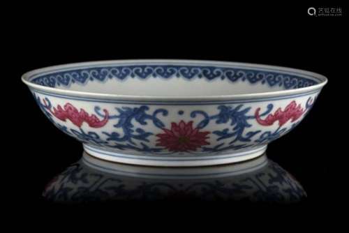 A blue and white and copper red porcelain saucer decorated with stylised lotus flowers, bats and