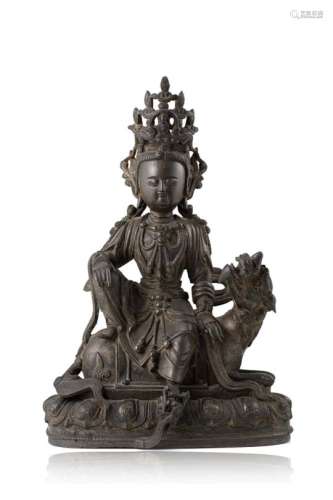 A bronze model of Guanyin wearing a crown and jewels, calligraphy incised to the base, seated on a