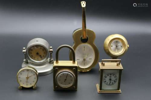 A group of five small clocks with a small thermometer