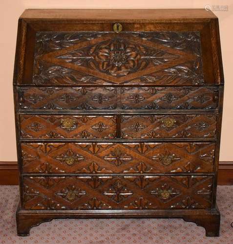 A VICTORIAN TUDOR STYLE OAK BUREAU, carved in relief