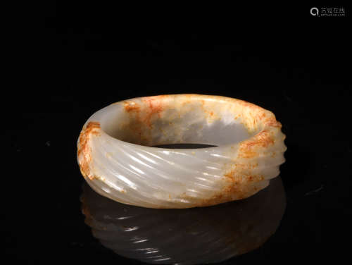 A TWISTED WHITE AND RUSSET JADE BANGLE